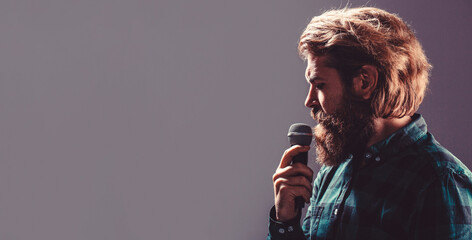 Wall Mural - Bearded man in karaoke sings a song into a microphone. Male attends karaoke. Bearded man singing with microphone. Male singing with a microphones