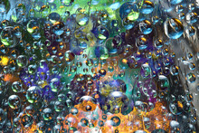 Transparent Raindrops Falling Down Against The Multicolored Background With Silhouettes Of Yellow- Blue Flowers. Abstract Fantasy. 