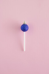 Wall Mural - Creative arrangement made of vivid blue Christmas bauble and lollipop stick on a pastel pink background. Minimal New Year flat lay concept. Candy inspiration..