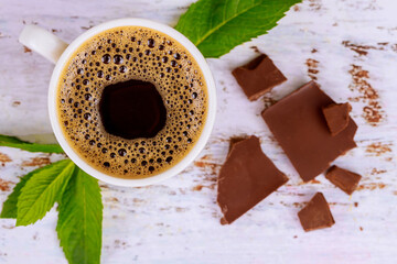 Wall Mural - Black coffee with milk chocolate on white wooden table.