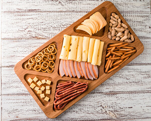 Wall Mural - Antipasto cold meat dish with breadsticks, prosciutto, ham, ham slices and cheese on a wooden tray