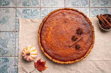 Wall Mural - American pumpkin pie with cinnamon on tile background, top view