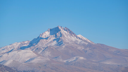 Wall Mural - Clouds on a volcanic Erciyes mount in Kayseri. Snowy scarlet mountain. Erciyes is a large stratovolcano, reaching a height of 3,864 m it the highest mountain and most voluminous volcano of Central Ana