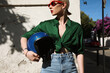 Cropped headshot of curvy caucasian biker woman posing in blue jeans. Outdoor.
