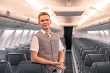 Male Flight Attendant Standing In Aircraft Passenger Salon