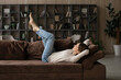 © fizkes - Peaceful young woman lying on comfy soft sofa with legs raised feels carefree spend lazy weekend alone at home. Day off, no stress, happy homeowner female enjoy pastime leisure at modern own apartment
