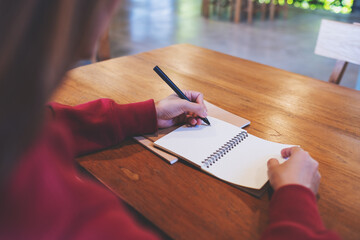 Wall Mural - Closeup image of a woman writing on a notebook on the table