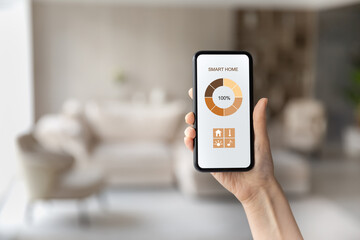 Close up cropped of woman using smartphone, controlling smart home systems in modern apartment, female hand holding mobile device with app interface, all house in phone, internet of things concept