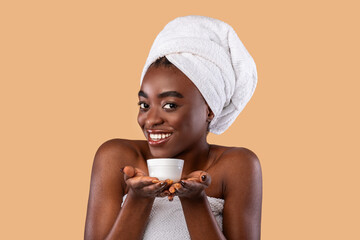 Wall Mural - Portrait of smiling black woman holding cream jar tube