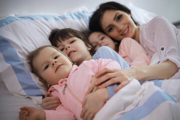 Wall Mural - A family with children having fun on the bed under the covers during the Christmas holidays.