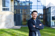 © Liubomir - portrait handsome Asian man a university college teacher, businessman, scientist or educator. Standing background modern office center or campus with arms crossed Outside, outdoors looking at camera