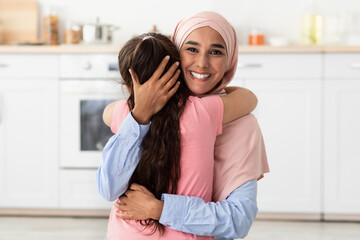 Wall Mural - Portrait Of Happy Smiling Islamic Lady In Hijab Cuddling Her Little Daughter