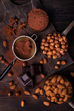 Still life. in the foreground with top view, vintage metal measuring spoons with shelled hazelnuts and almonds, cocoa powder, pieces of dark chocolate and star anise stars