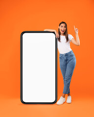 Wall Mural - woman pointing up leaning on big white empty smartphone screen
