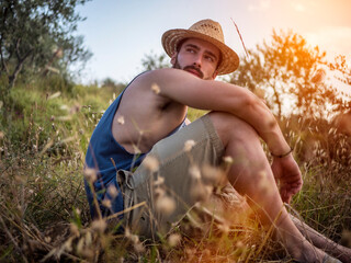 Male model relaxing, sitting in a field