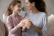 © fizkes - Close up happy mother with smiling little daughter holding pink piggy bank sitting on couch at home, caring mom and adorable girl child saving money for future, family insurance and investment