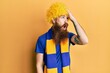 © Krakenimages.com - Redhead man with long beard football hooligan cheering game wearing funny wig surprised with hand on head for mistake, remember error. forgot, bad memory concept.