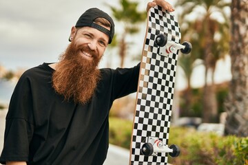 Sticker - Young irish skater man smiling happy holding skate at the city.