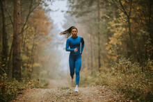 Young Woman Running Toward Camera On The Forest Trail At Autumn