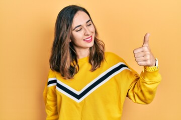 Poster - Young hispanic girl wearing casual clothes looking proud, smiling doing thumbs up gesture to the side