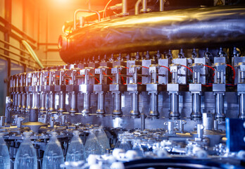 Wall Mural - Automatic filling machine pours water into plastic PET bottles at modern beverage plant.