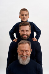 Narrow portrait of three generations of men posing