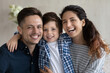 © fizkes - Head shot portrait happy hispanic couple and preschool son sit on sofa at home smiling looking at camera. Bank loan, medical insurance cover for young family, dental services satisfied clients concept