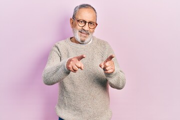 Poster - Handsome senior man with beard wearing casual sweater and glasses pointing fingers to camera with happy and funny face. good energy and vibes.