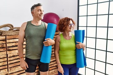 Sticker - Middle age couple holding yoga mat looking away to side with smile on face, natural expression. laughing confident.