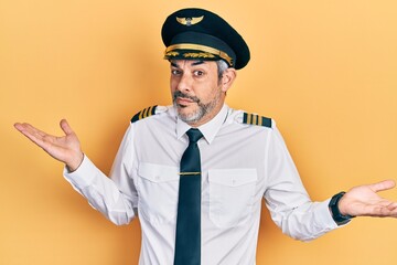 Sticker - Handsome middle age man with grey hair wearing airplane pilot uniform clueless and confused expression with arms and hands raised. doubt concept.