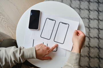 Designer is developing a UX mobile application wireframe. Sketch, prototype, framework, layout future app design for smartphone. UI/UX - user interface and user experience designer. App development