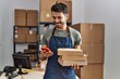© Krakenimages.com - Young hispanic man business worker using smartphone holding packages at storehouse