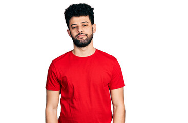 Poster - Young arab man with beard wearing casual red t shirt relaxed with serious expression on face. simple and natural looking at the camera.