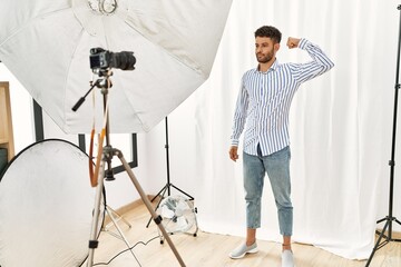 Sticker - Arab young man posing as model at photography studio strong person showing arm muscle, confident and proud of power