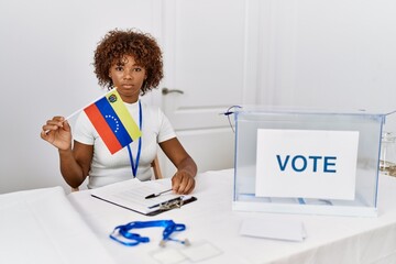 Sticker - Young african american woman at political campaign election holding venezuela flag thinking attitude and sober expression looking self confident