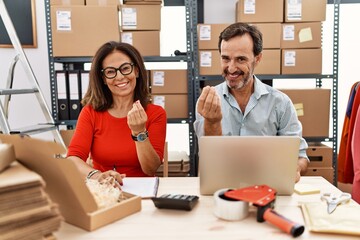 Canvas Print - Middle age couple working at small business ecommerce doing money gesture with hands, asking for salary payment, millionaire business