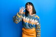 © Krakenimages.com - Young hispanic woman wearing casual winter sweater showing and pointing up with fingers number four while smiling confident and happy.