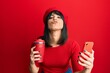 © Krakenimages.com - Young hispanic woman using smartphone and drinking a cup of coffee looking at the camera blowing a kiss being lovely and sexy. love expression.