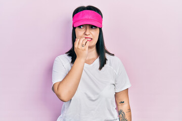 Sticker - Young hispanic woman wearing sportswear and sun visor cap looking stressed and nervous with hands on mouth biting nails. anxiety problem.