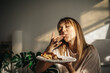 © Oleksii - Attractive girl eating croissants in a bright room. Beautiful girl eating croissants with chocolate for breakfast
