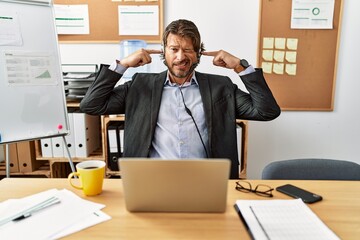 Sticker - Handsome middle age man wearing call center agent headset at the office covering ears with fingers with annoyed expression for the noise of loud music. deaf concept.