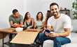 © Krakenimages.com - Group of young hispanic friends eating italian pizza sitting on the sofa. Man smiling happy and using smartphone at home.