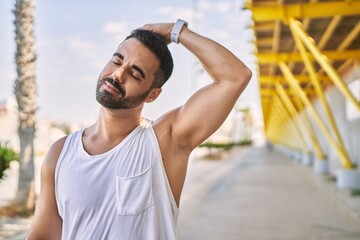 Poster - Hispanic man stretching neck after working out outdoors on a sunny day