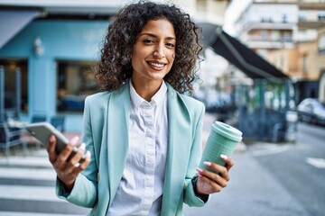 Wall Mural - Young hispanic business woman wearing professional look smiling confident at the city using smartphone