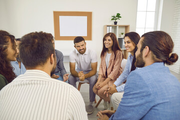 Wall Mural - Different people sitting in a circle, talking and smiling during a group therapy session. Team of happy cheerful positive young and mature men and women having a meeting