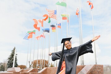 Wall Mural - pretty african college student in graduation cap and gown in front of school building