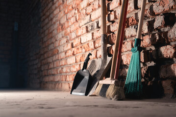 Wall Mural - Broom and dust pan on the dirty dusty floor of a construction site room background.