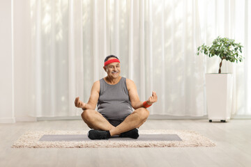 Sticker - Mature man with a head band sitting on an exercise mat and practicing yoga