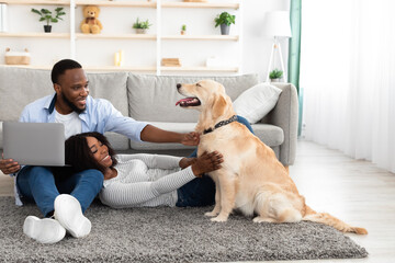 Poster - Young black couple at home using laptop playing with labrador