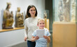 © JackF - Portrait of cheerful young woman with school age boy exploring artworks in museum and having fun
